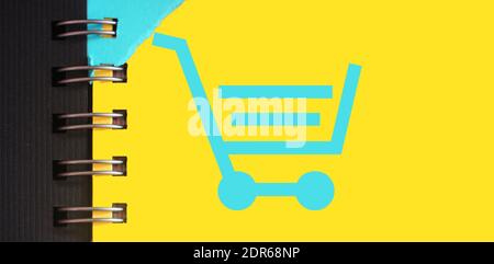 Shopping cart symbol on yellow page of copybook in white and blue. Online shopping or internet shop concept Stock Photo