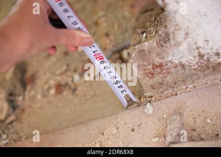 measuring the distance of the wall for repair. Iron roulette tape with numbers. Construction and restoration. Stock Photo