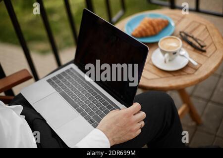 Young businessman using a laptop while coffee break at the cafe table Stock Photo