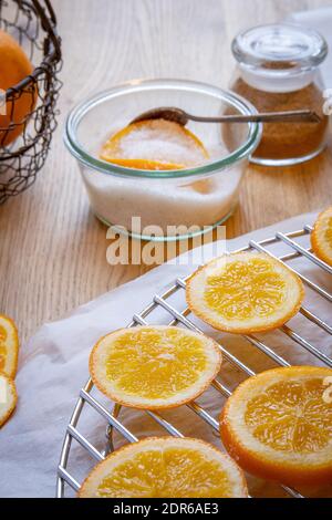 A bowl of sugar with an orange slice and a spoon, gingerbread spice mix, and orange slices drying on a rack. Stock Photo
