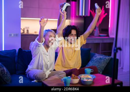 Photo of young couple playing video games at home at night Stock Photo