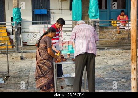 Chennai, South India - October 27, 2018: Hindu devotee performing prayer ritual with candles ( diya ) inside a hindu temple located in Tamil Nadu stat Stock Photo