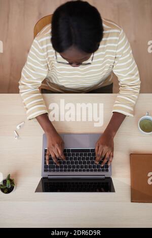 Top view portrait of young African-American woman using laptop while sitting at desk in home interior Stock Photo