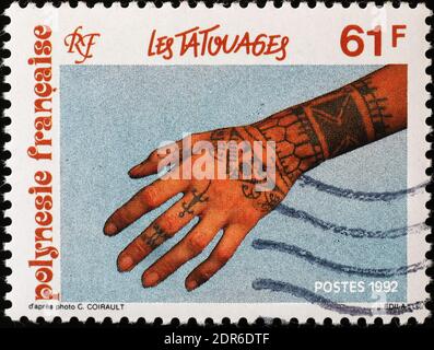 Tattoed hand of woman on stamp of French Polynesia Stock Photo