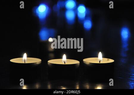 Christmas candles burning at night.  Golden light of candle flame. Decoration, black.Abstract candles background. Stock Photo