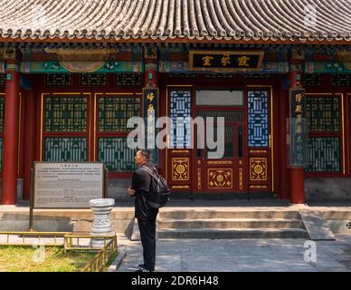 Beijing, China April 3, 2016 -- A man stands on the pavement, outside the main building. Stock Photo