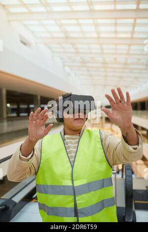 Vertical waist up portrait of female engineer wearing VR headset while visualizing architectural design project Stock Photo