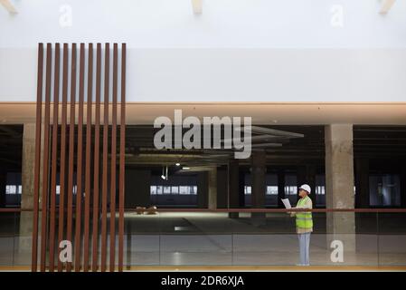 Graphic wide angle view at female engineer holding blueprints while working on construction site, with focus on architectural design, copy space Stock Photo