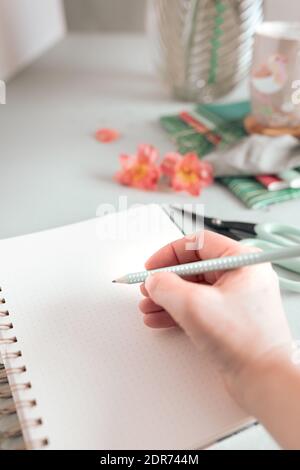 Woman hand writing in an empty spiral notebook with a dotted pencil. Stock Photo