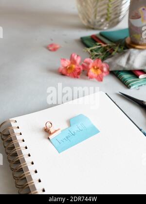 Empty spiral notebook with a dotted pencil and an important note clamped at the top of it. Stock Photo