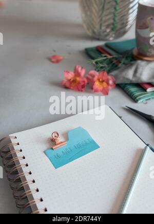 Empty spiral notebook with a dotted pencil and a Do Not Forget note clamped at the top of it. Stock Photo