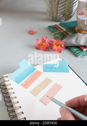 Empty spiral notebook with a dotted pencil held by a woman hand and several reminder notes at the top of it. Stock Photo