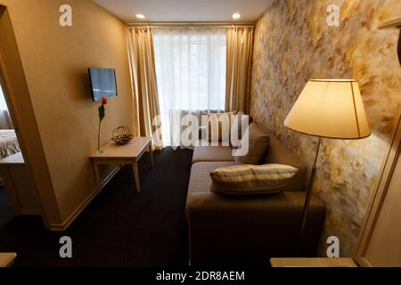 The interior of the hotel room in brown colors. A cozy sofa stands opposite a small living room in a hotel room Stock Photo
