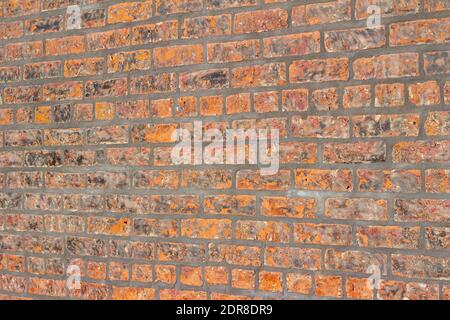 Full frame texture background of a shabby chic hot orange color brick wall with an attractive weathered surface in fiery shades of orange and brown Stock Photo