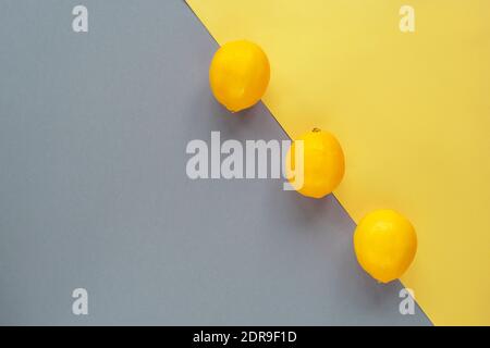 Lemons on yellow and gray background. Trendy colors 2021. Minimal composition, flat lay, copy space.j Stock Photo