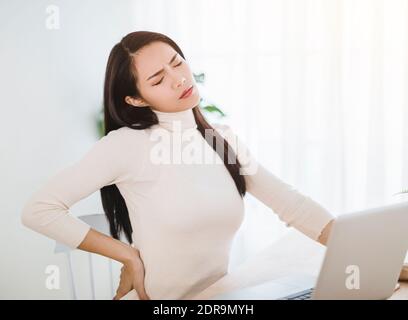 young woman suffering from backache after working on laptop Stock Photo
