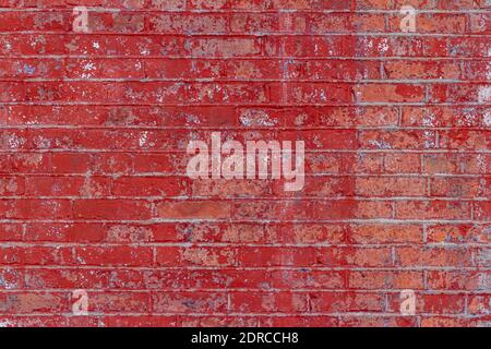 Full frame shabby chic view of an eroding antique exterior brick wall surface with rosy red painted bricks Stock Photo