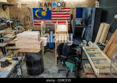 (201221) -- KUALA LUMPUR, Dec. 21, 2020 (Xinhua) -- A worker is busy at Kawood workshop on the suburbs of Kuala Lumpur, Malaysia, Dec. 17, 2020. Mohamad Hafiz Johari, together with two other former photographers Abdul Razak Abdul Latif and Noor Adzrene Mohd Noor, came together to set up Kawood, a combination of the Malay word kawan (friend) and wood, with all three having lost their source of income due to disruptions caused by the COVID-19 pandemic. Undeterred, they brainstormed some means of making a living, ultimately deciding on putting their enthusiasm for construction into building and Stock Photo