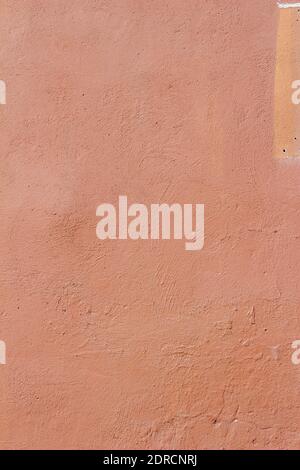 Full frame abstract background of an eroding exterior concrete stone wall with cracked and peeling red painted stucco plaster surface texture Stock Photo