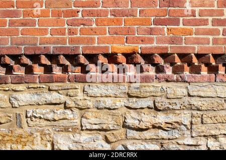 Texture background of a rugged old exterior red clay brick and white limestone wall with accent rows of pointed red clay bricks in between the layers Stock Photo