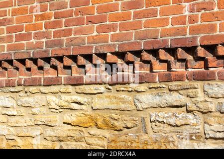 Texture background of a rugged old exterior red clay brick and white limestone wall with accent rows of pointed red clay bricks in between the layers Stock Photo