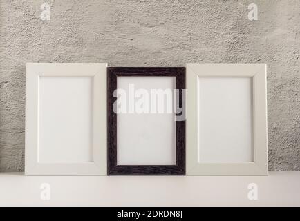 Three empty photo frames in a dark and light frame on a table or shelf with a copy of the place. Stock Photo