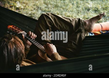 Man Playing Guitar While Sitting In Hammock