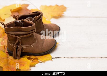 Female brown shoes satanding on white wooden table with yellow autumn leaves Stock Photo