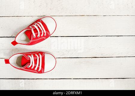 Little red sneakers on white wooden background with a copy space Stock Photo