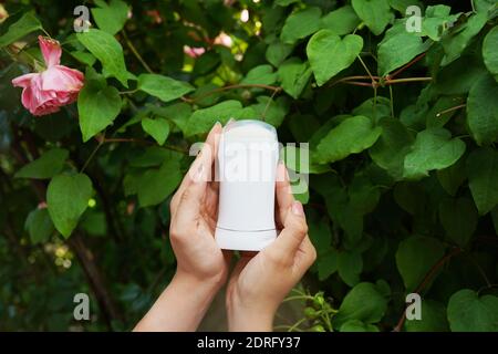 Woman's hands holding deodorant for armpit skin in natural background Stock Photo