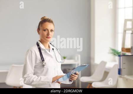 Portrait of a confident young female doctor standing with a clipboard in her hands. Stock Photo