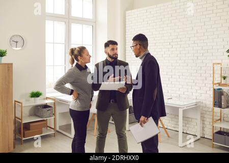 Serious office workers of different nationalities discuss the project together in a bright office. Stock Photo