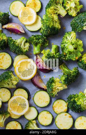 Raw chopped broccoli, zucchini, and onions on a baking sheet. Cooking green vegetables for baking in the oven. Cooking healthy food concept. Stock Photo
