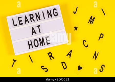 Learning at home message on lightbox and letters on yellow background. Online learning, remote education at home concept Stock Photo