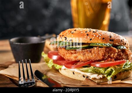 The concept of American fast food. A juicy American burger with two beef patties and a dark beer on wooden background. Copy space. Stock Photo