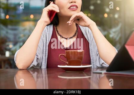 Woman talking on phone in cafeteria Stock Photo