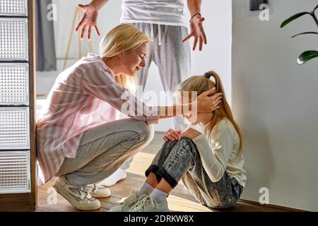 kid girl is suffering from quarrels between parents in the family at home, woman and man argue in the presence of daughter Stock Photo