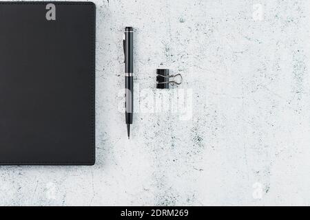 Office desk with black notepad and pen on gray background. Top view with copy space. Business goals and objectives concept Stock Photo
