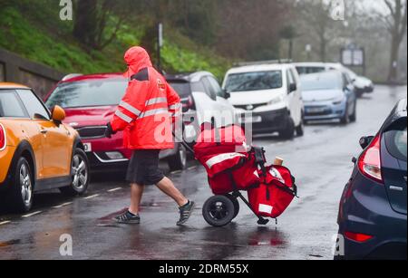 Brighton UK 21st December 2020 - A postman delivering Christmas post and parcels in Brighton still wearing his shorts despite the rain and wind today : Credit Simon Dack / Alamy Live News Stock Photo