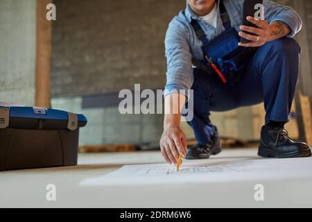 Close up of female construction worker pointing at blueprints while working in apartment building, copy space Stock Photo