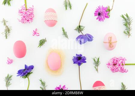 Ester holiday composition with colorful eggs, spring flowers, hypericum and leaves of lavender on white background. Flat lay, top view Stock Photo