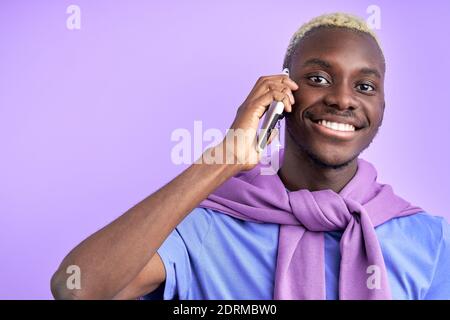 nice pleasant black man talk on phone isolated in studio on purple background, smile, listen to interlocutor Stock Photo