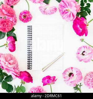 Floral frame of pink roses on white background. Flat lay, top view. Flower composition with notebook and pen Stock Photo