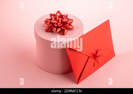 Pink round gift box and red envelope on pink background Stock Photo