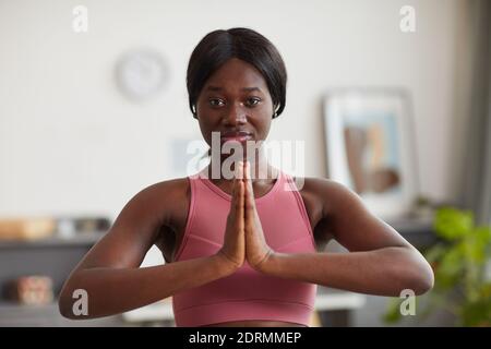 Front view portrait of young African-American woman looking at camera while practicing yoga and wellness at home Stock Photo
