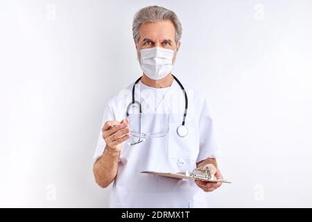 doctor man wearing protective eyeglasses for preparing for work, elderly male in white medical suit looks at camera isolated on white background Stock Photo
