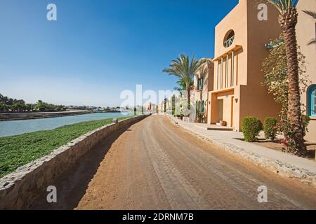 View along a sandy dirt road through beautiful landscaped gardens in tropical hotel resort with river Stock Photo