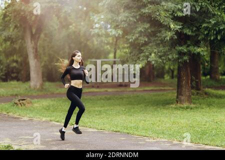 A young woman in sportswear is engaged in morning running in the open air. The concept of a healthy lifestyle. Stock Photo