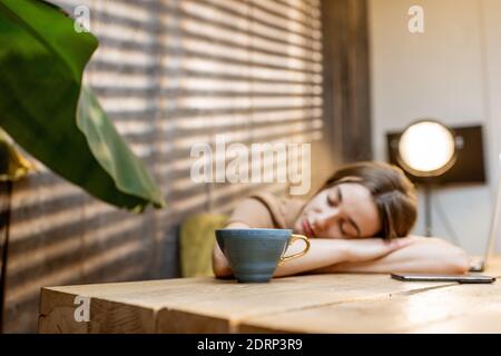 Sleepy woman at the workplace at home. Cozy workplace at home, the concept of fatigue from work at home Stock Photo