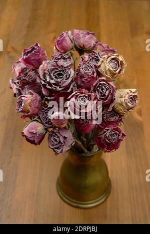 a bouquet of dry roses in a copper coffee turk on a wooden table Stock Photo